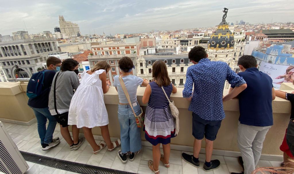 Fotografía. Vista posterior de un grupo de jóvenes asomados a una terraza.