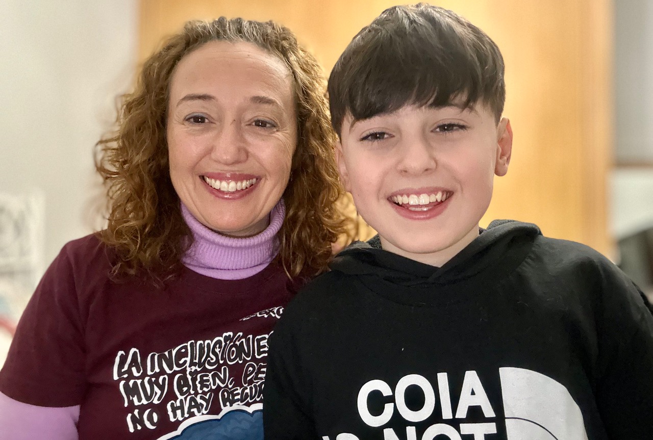 Retrato de Paula Verde y su hijo Lucas, sonriendo. Paula luce una camiseta de la Campaña "Excusas" de "Quererla es Crearla"