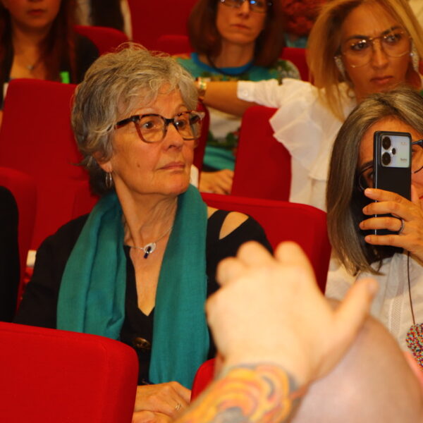 Fotografía. Una mujer escucha sentada en el salón de actos durante una asamblea.