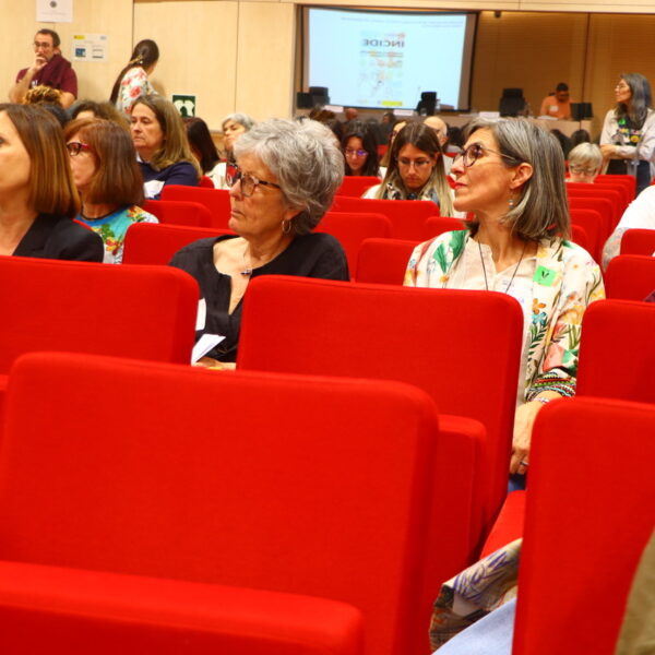 Fotografía. Varias personas escuchan sentadas en el salón de actos durante una asamblea.