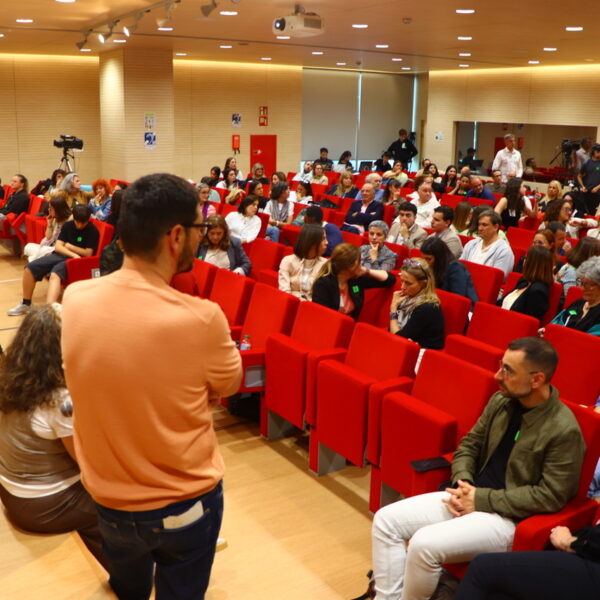 Fotografía. Debate en el salón de actos del ministerio, una sala amplia con buena iluminación y asientos plegables con tapicería de tela roja. Hay mucha gente y una persona toma la palabra.