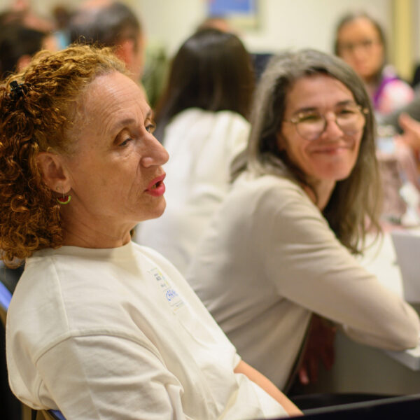 Fotografía. Participantes en una mesa de reuniones debaten y sonríen.