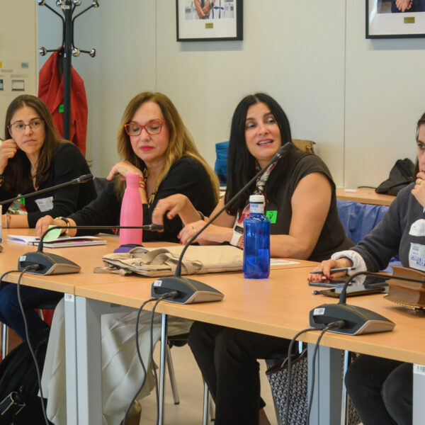 Fotografía. Participantes en una mesa de reuniones debaten y toman notas.